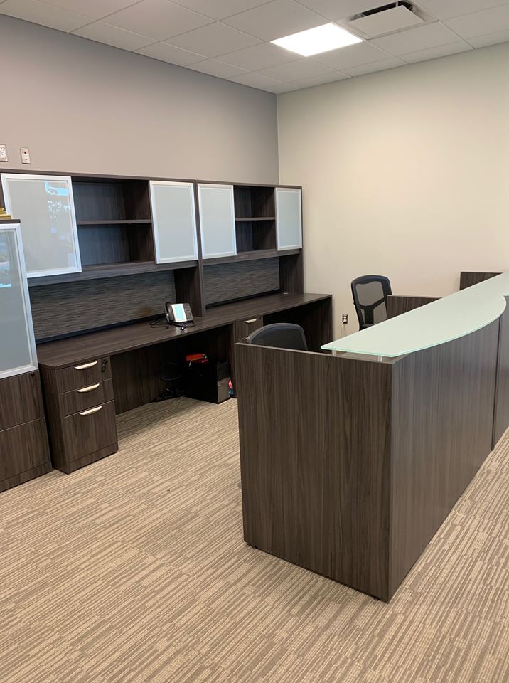 Reception area with a glass-top reception desk and a matching credenza with overhead hutch storage