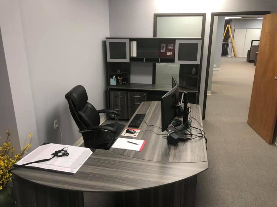 Private office with an L-shaped desk, leather executive chair, and a credenza with a frosted-glass hutch