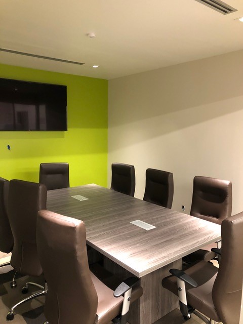 Conference room with a gray laminate table, brown leather chairs, and a wall-mounted display