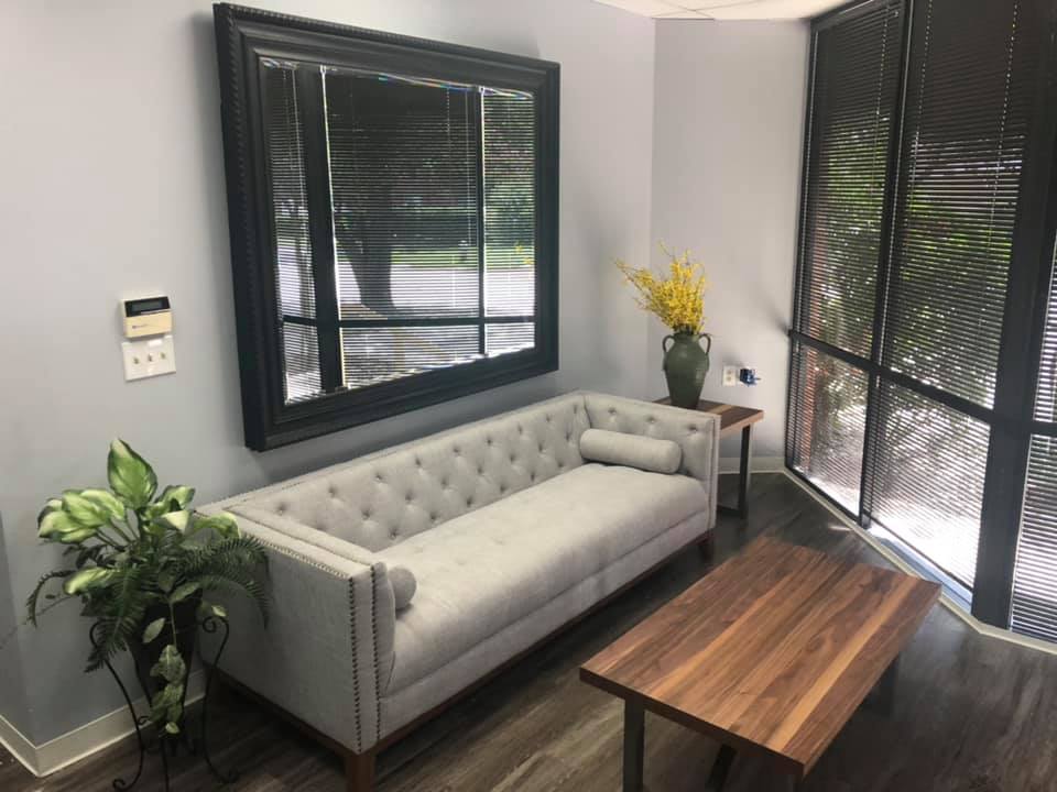 Reception lobby with a gray tufted sofa, walnut coffee table, and end table