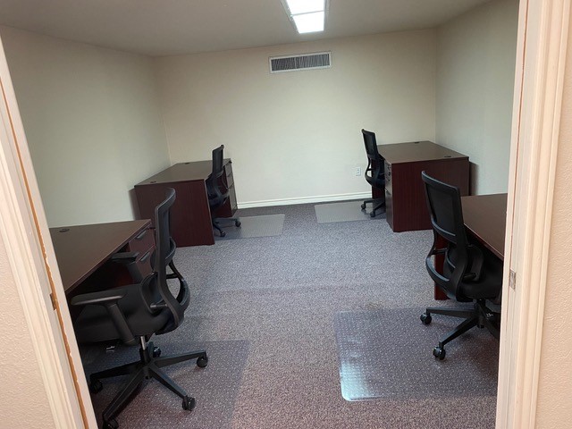 Shared office with multiple mahogany desks and black mesh task chairs