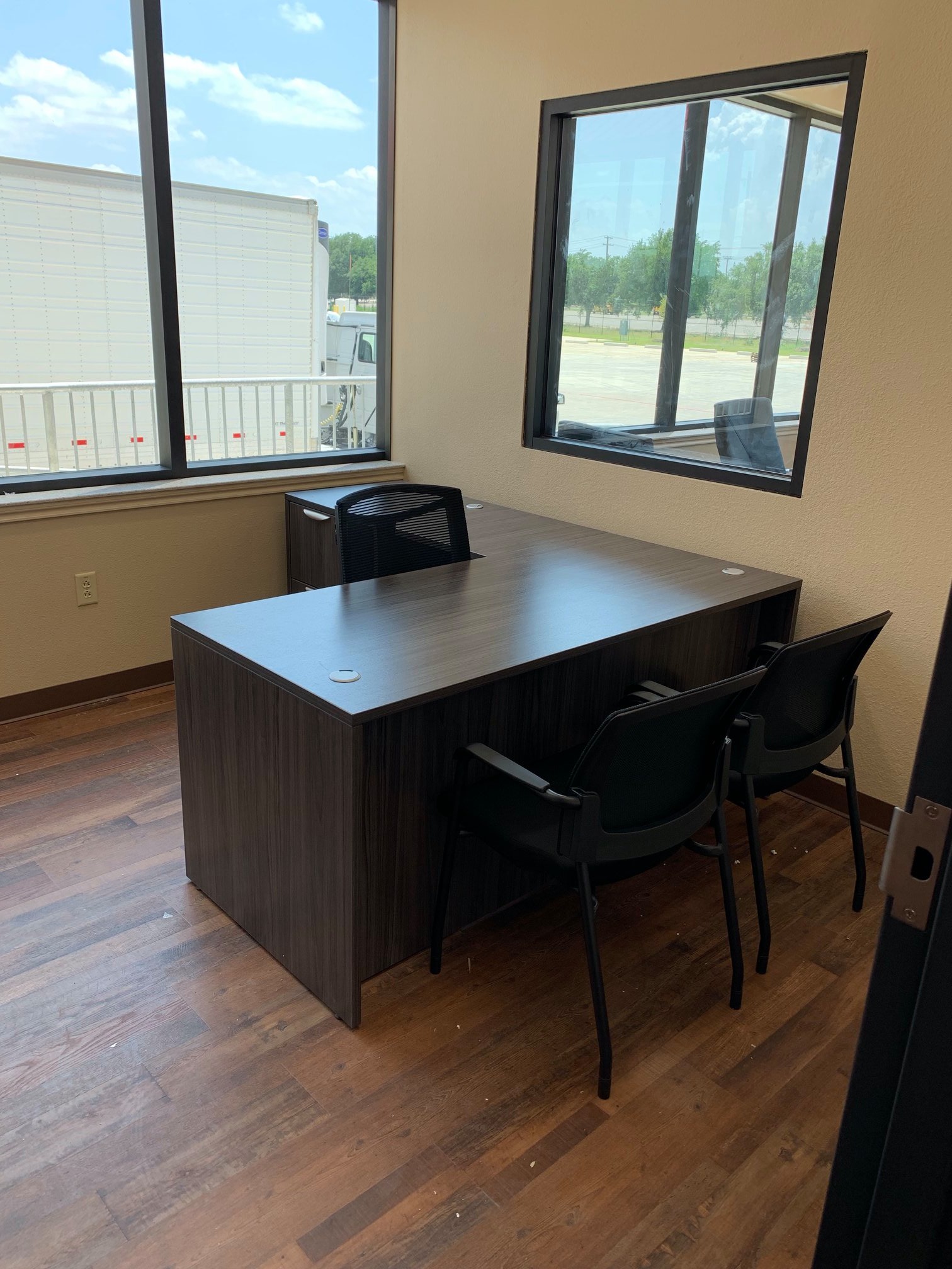 Private office with an espresso bow-front desk and black mesh guest chairs