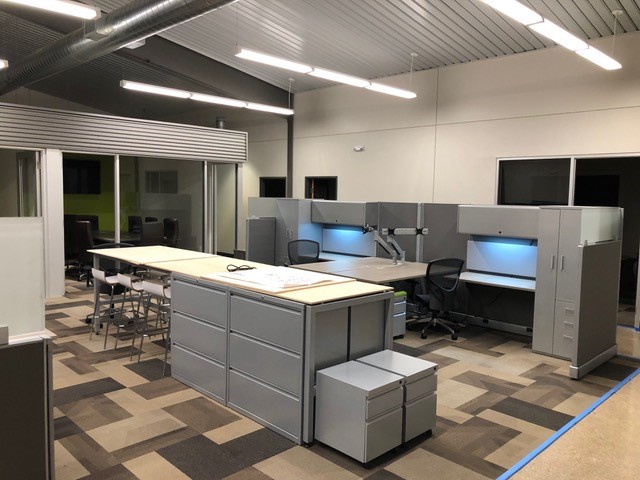 Open office workstations with task lighting and a collaborative layout table