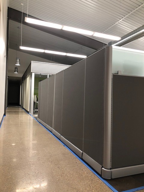 Run of tall gray cubicle privacy panels along an office corridor